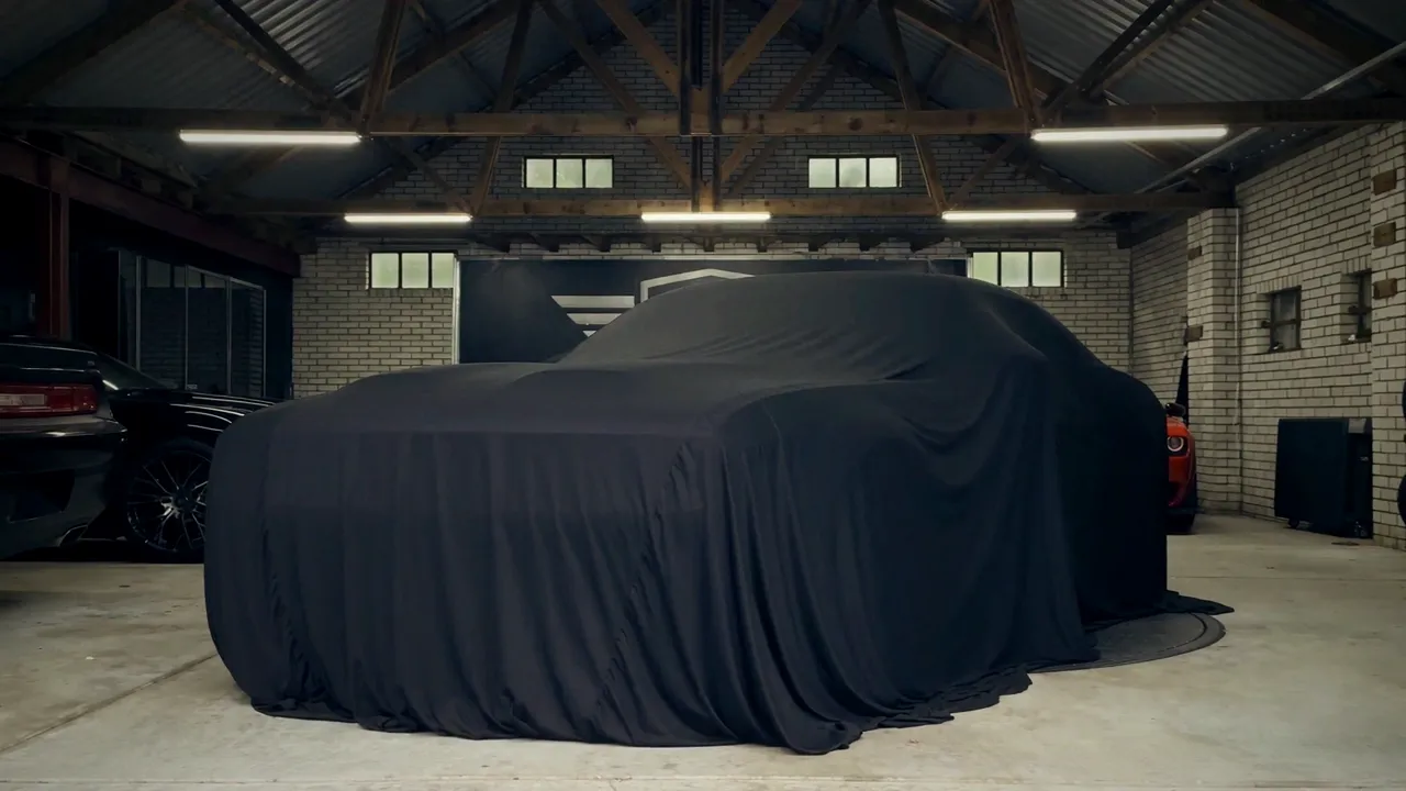 Dodge Challenger onder een zwarte hoes in de werkplaats van Marlon&rsquo;s Prestige Cars